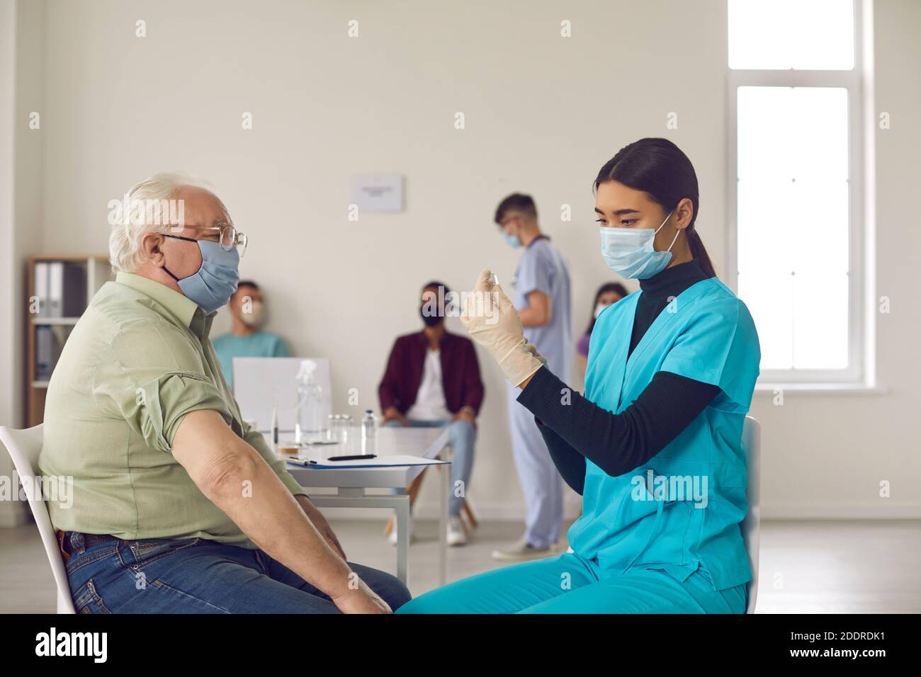 Paziente anziano in maschera in attesa di ricevere un vaccino contro l'influenza, la polmonite o Covid-19 Foto Stock