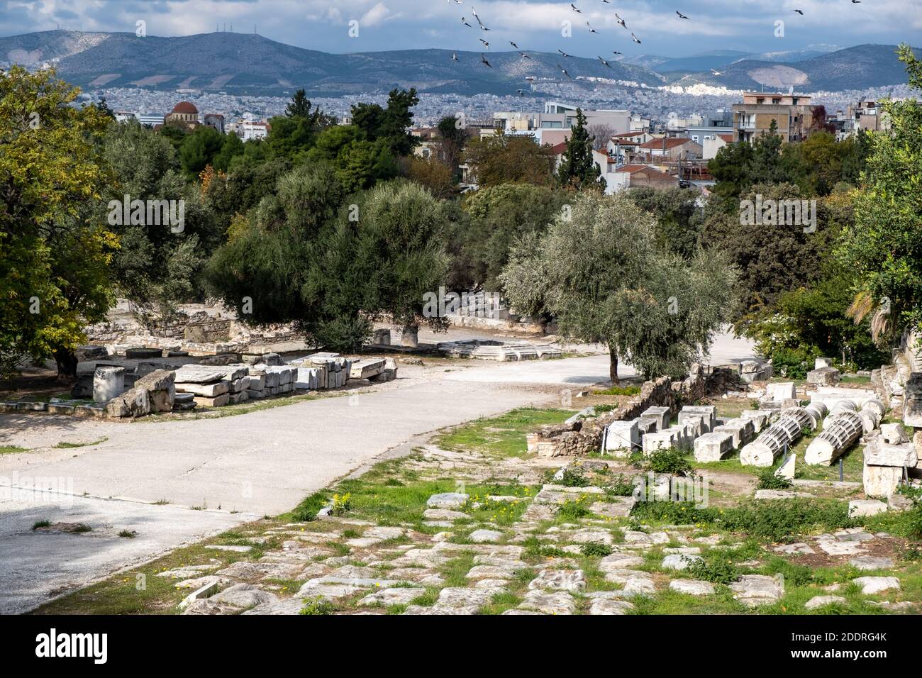 Atene Grecia, agora romana. Antiche rovine, colonne di marmo accatastate sul terreno, il paesaggio urbano di Atene e lo sfondo del cielo nuvoloso Foto Stock