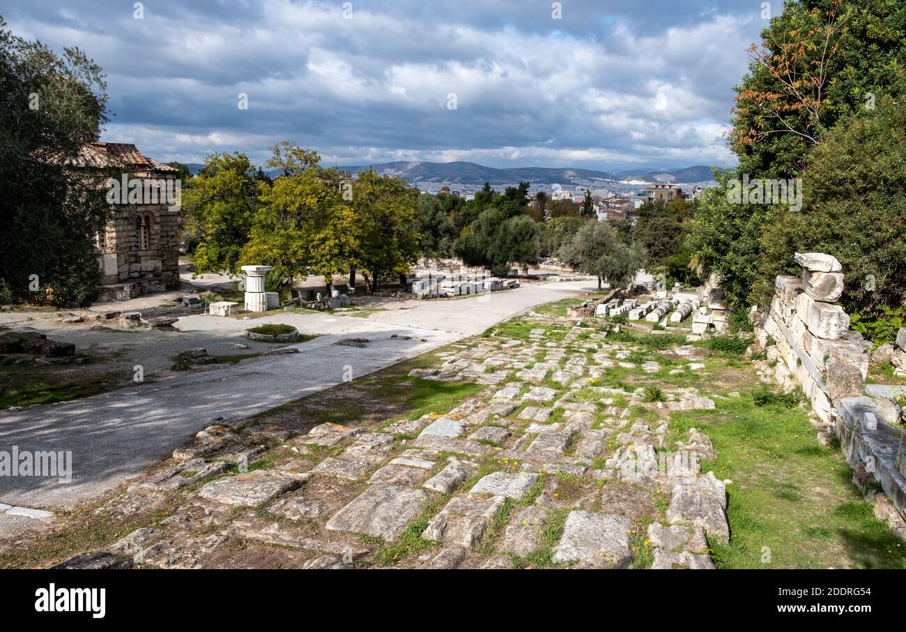 Atene Grecia, agora romana. Antiche rovine, colonne di marmo accatastate sul terreno, il paesaggio urbano di Atene e lo sfondo del cielo nuvoloso Foto Stock