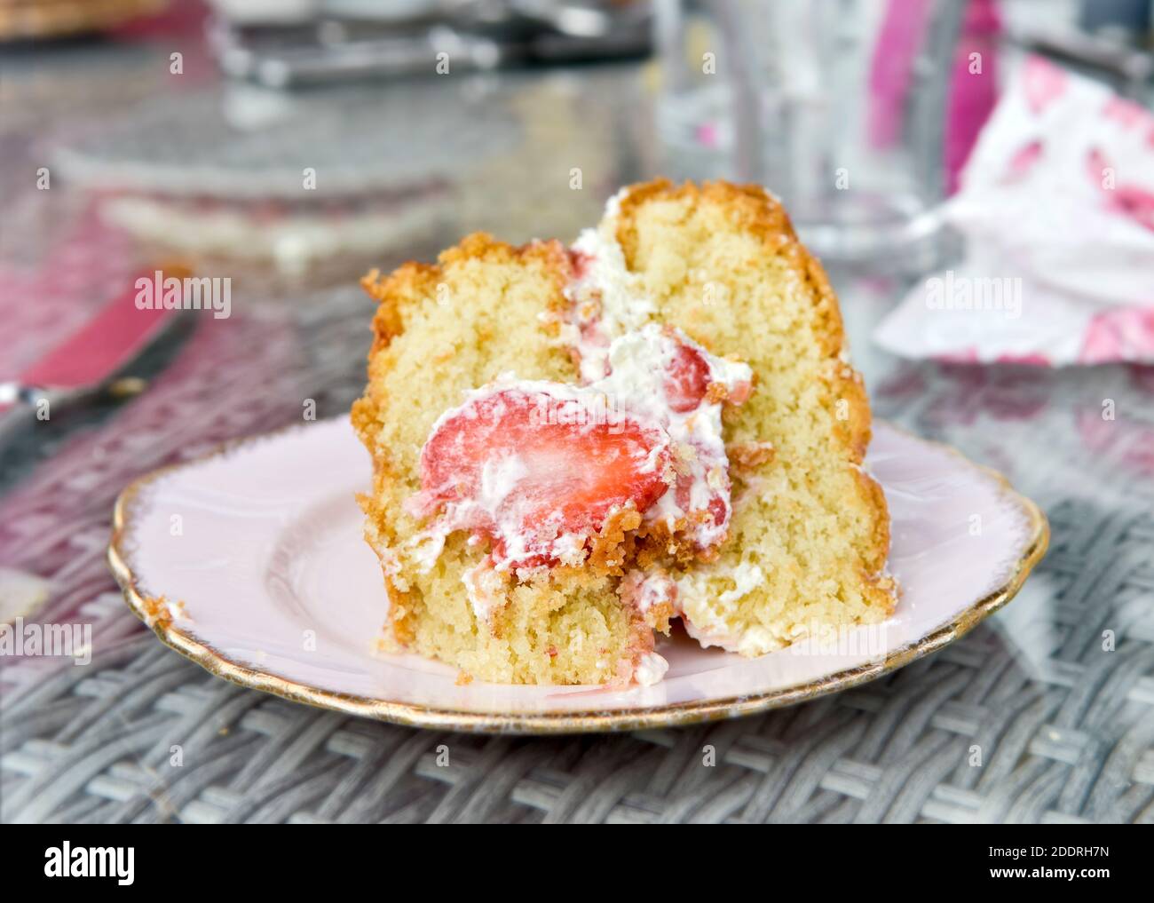 Bella fetta grande di leggera torta di spugna Victoria fatta in casa con fragole e panna fresca al centro, con bocconcini fuori angolo Foto Stock