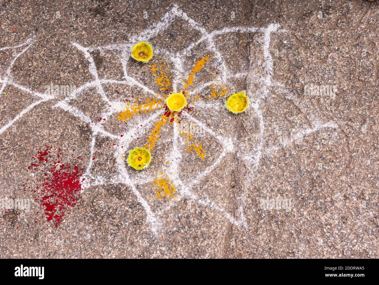 Hampi, Karnataka, India - 4 novembre 2013: Complesso del Tempio di Virupaksha. Closeup di bianco-arancio kolam dipinto di simbolo di loto disegnato su marciapiede marrone. Foto Stock