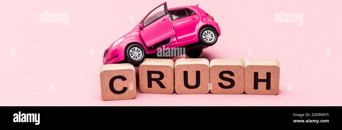 auto giocattolo e la parola schiacciano su cubi su sfondo rosa, banner Foto Stock