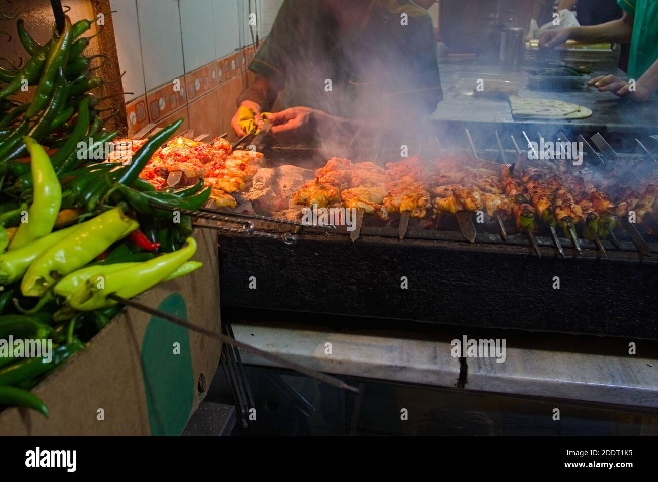 Kebab alla griglia, cibo turco di strada. Ali di pollo sulla strada. Ali di pollo arrostiscono alla griglia nel bar sulla strada. Peperoncino verde Foto Stock