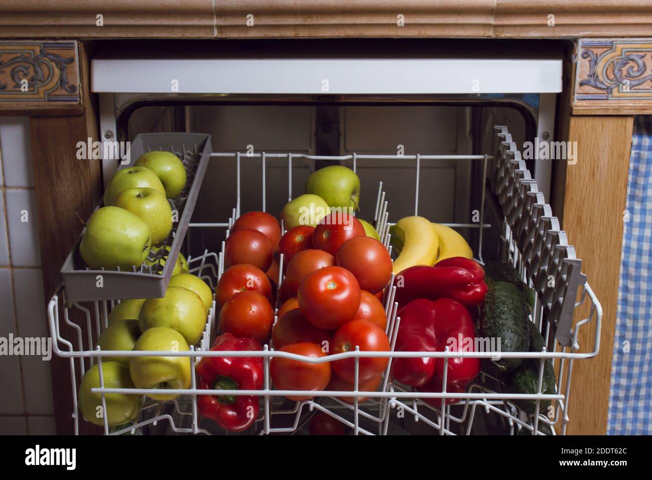 Set di frutta e verdura all'interno di una lavastoviglie di una cucina rustica in pietra, legno e piastrelle. Disinfezione concettuale di alimenti, frutta e verdura. Foto Stock