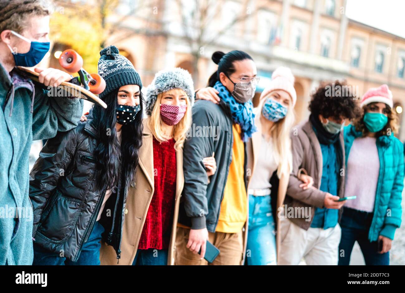 La gente millenaria cammina e si diverte a indossare il viso Maschera al centro della città - nuovo concetto di amicizia normale con amici multiculturali Foto Stock