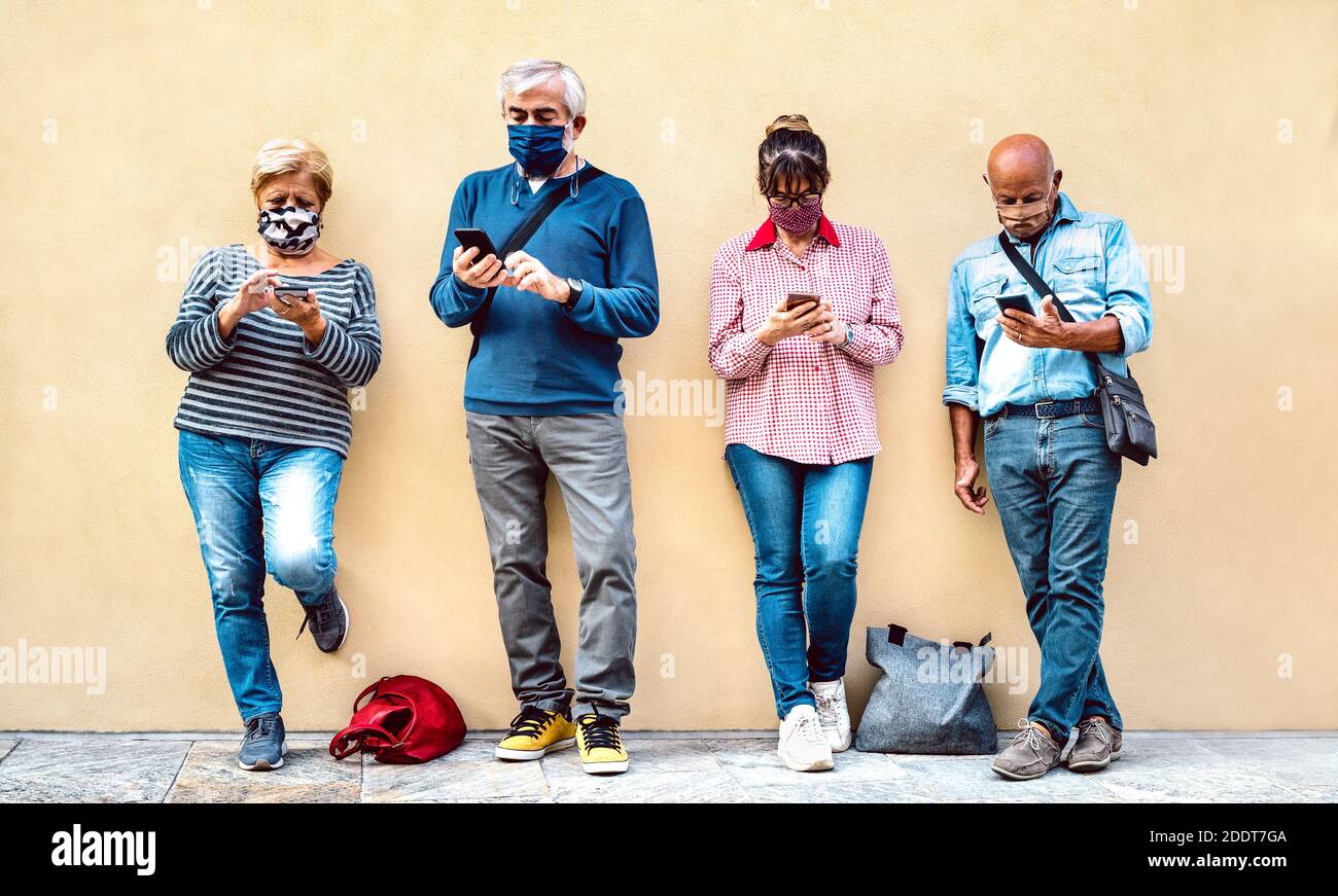 Persone anziane che utilizzano smartphone con maschera coperta - amici ritirati che condividono contenuti sullo smartphone - nuovo normale concetto di stile di vita Foto Stock