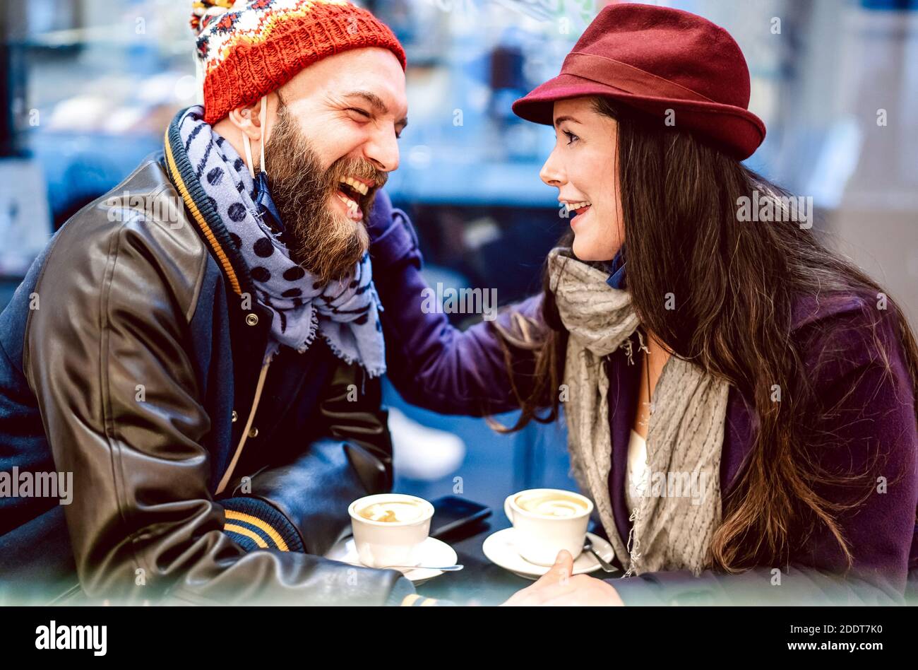 Gente felice che parla e che si diverte insieme al bar caffetteria - concetto di stile di vita invernale con giovane coppia di umore genuino bere caffè italiano Foto Stock
