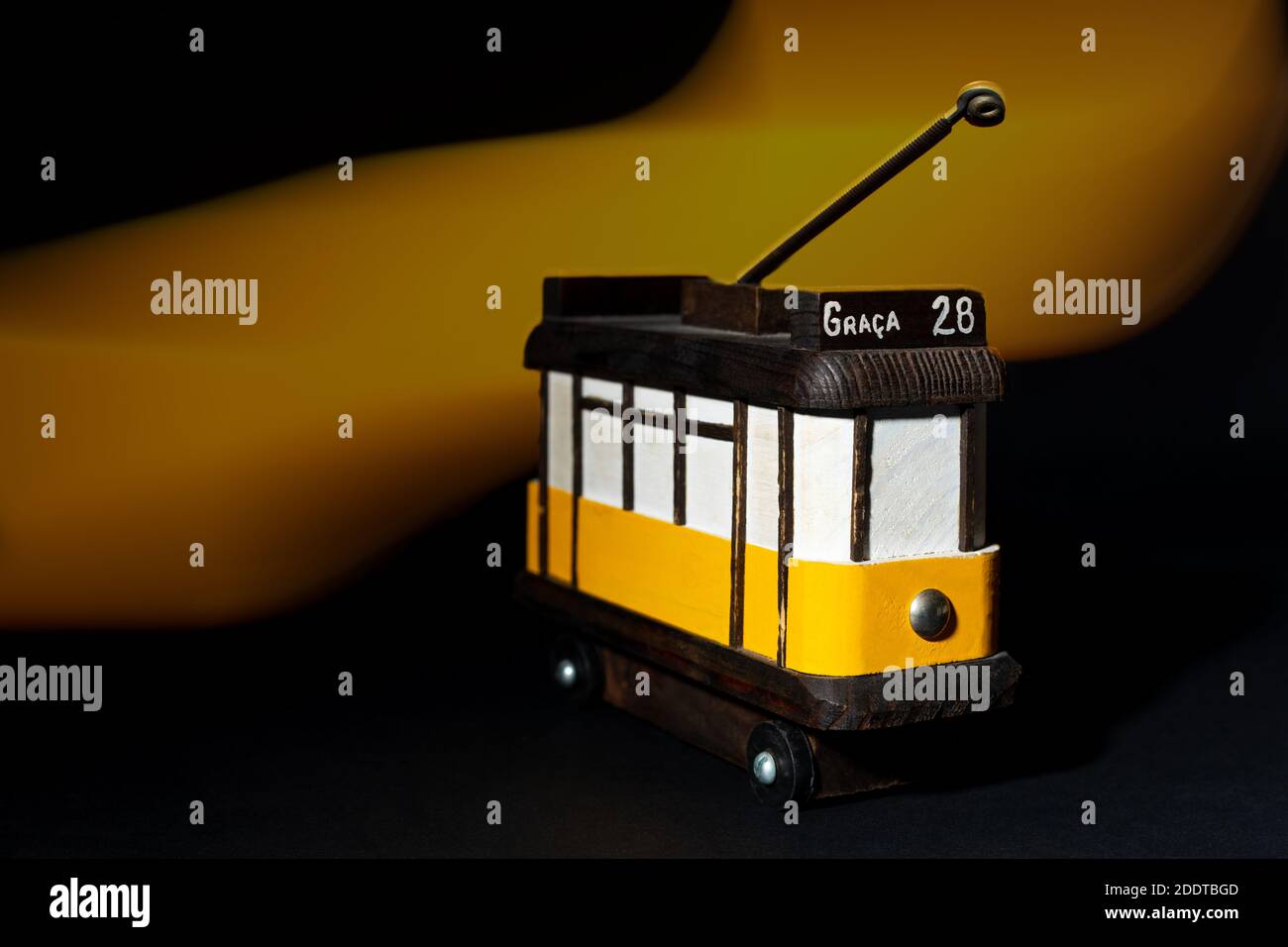 Piccolo modello in legno del tram giallo 28 di Lisbona con effetto luminoso sullo sfondo. Foto Stock
