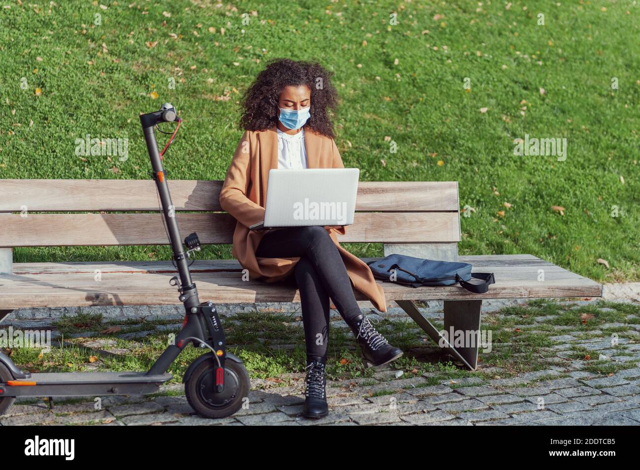 Donna seduta che lavora con il laptop e lo scooter elettrico Life Style indipendenza stile di vita sano Foto Stock
