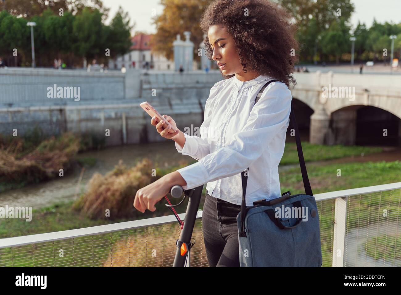 Giovane donna scarica l'app per usare lo scooter elettrico in città strada sano stile di vita sostenibile stile di vita Foto Stock