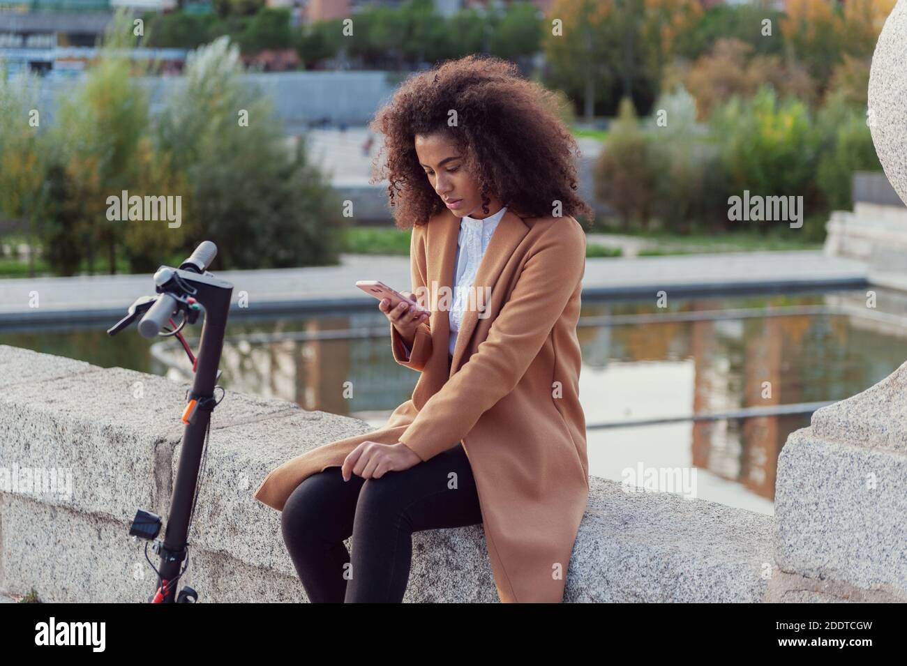 Giovane donna scarica l'app per usare lo scooter elettrico in città strada sano stile di vita sostenibile stile di vita Foto Stock