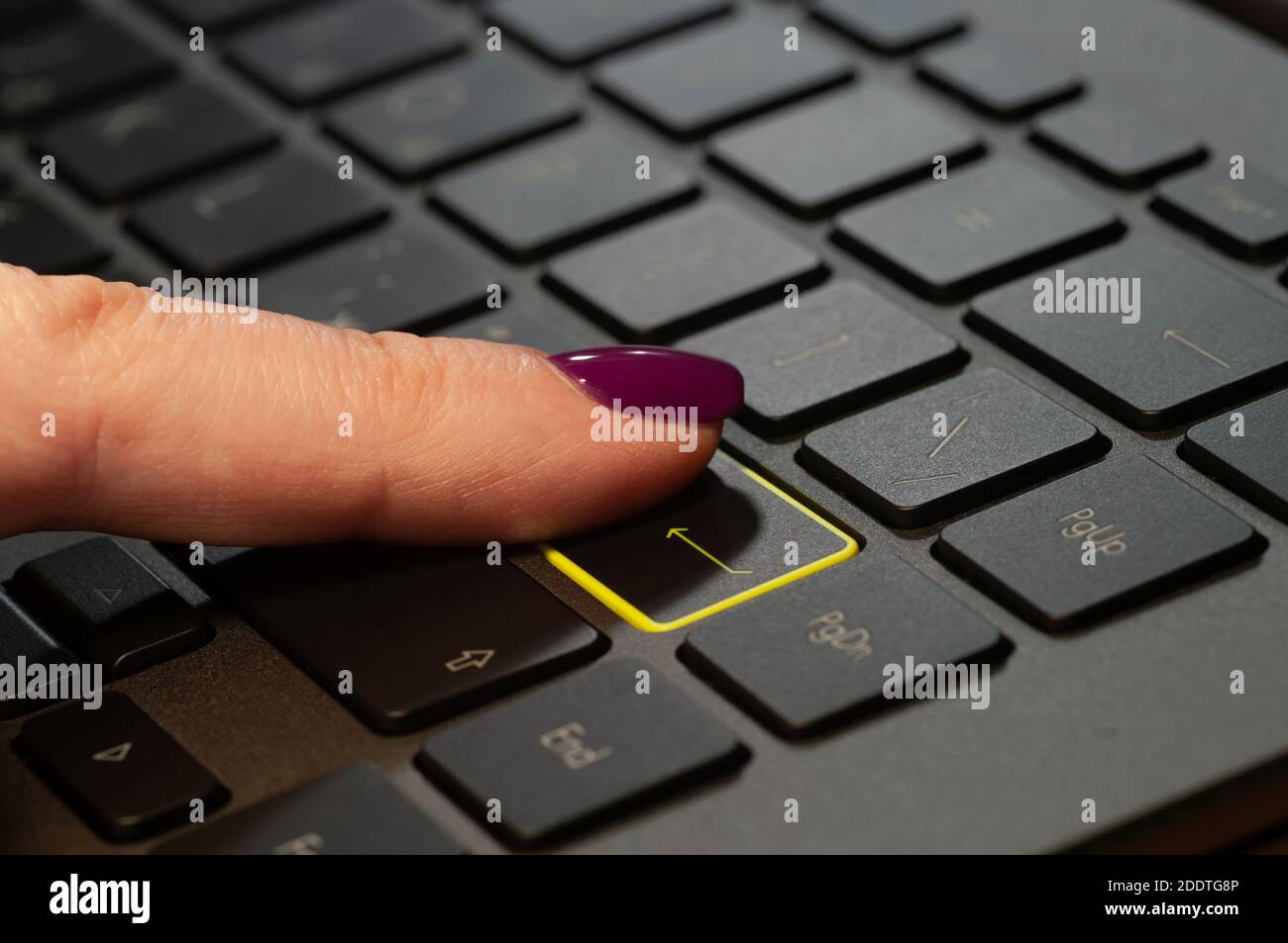 Primo piano con il dito della donna premendo il tasto Invio sulla tastiera del portatile. Foto Stock