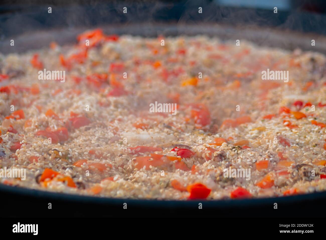 Processo di cottura dei gamberetti di paella, della cozza, del riso, del pomodoro in una padella enorme - primo piano Foto Stock