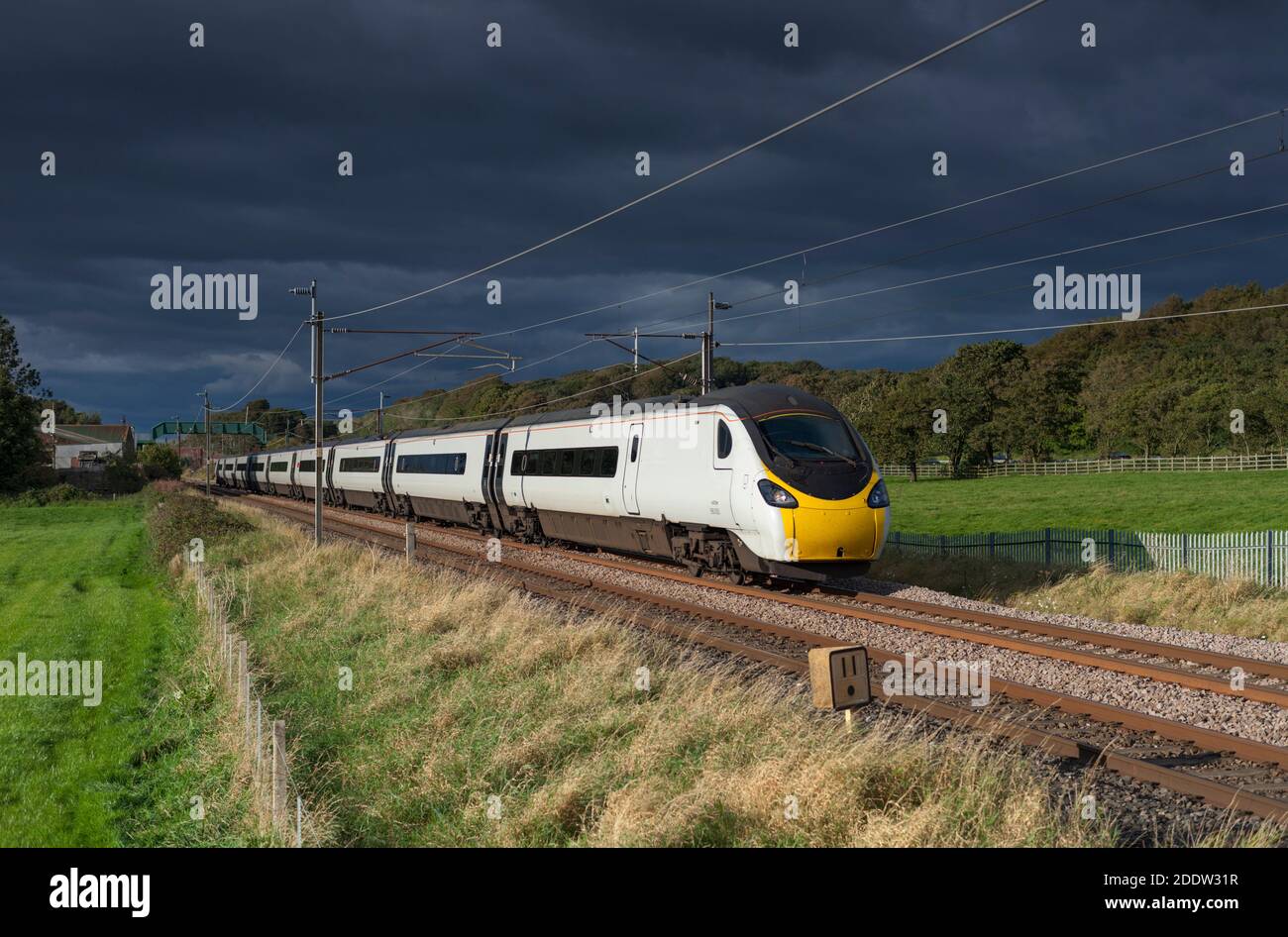 Avanti costa ovest Alstom Pendolino treno 390005 ad ovest Linea principale della costa del Lancashire con un cielo nero tempestoso alle spalle Foto Stock