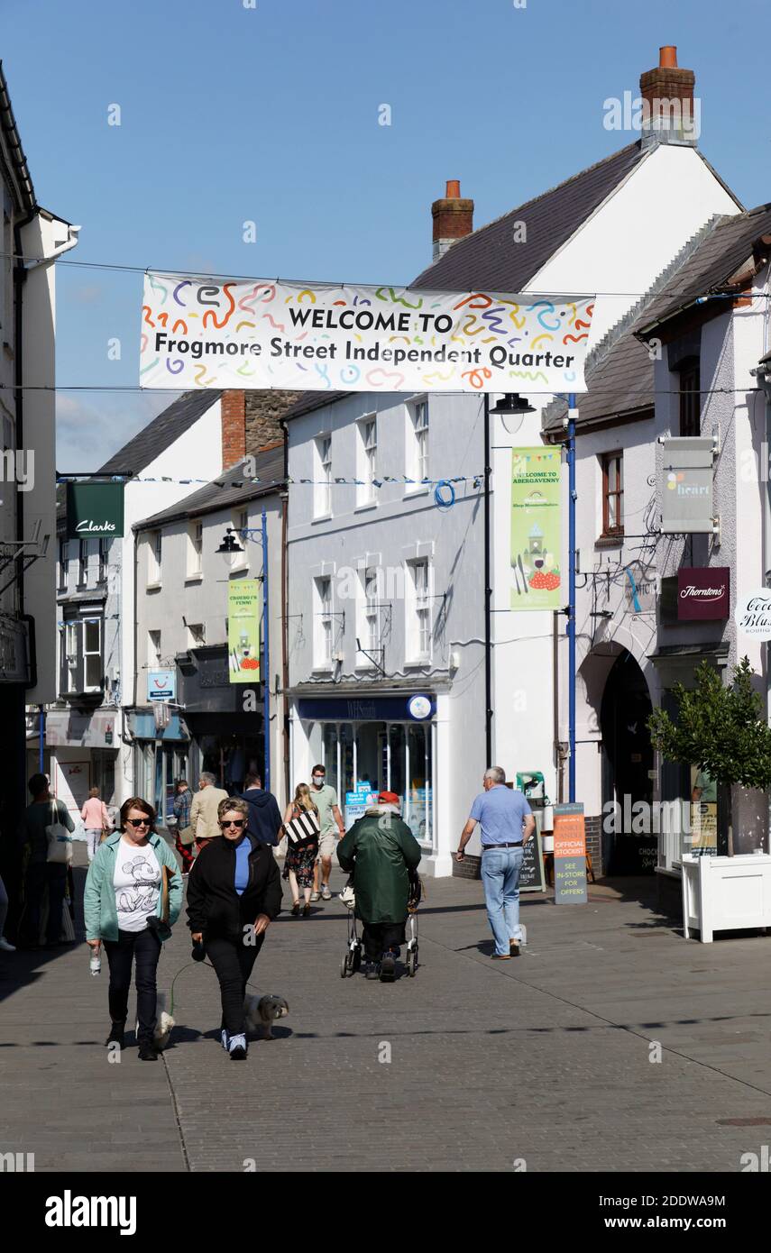 Via dello shopping con cartello di benvenuto per il quartiere indipendente, Abergavenny, Galles, Regno Unito Foto Stock