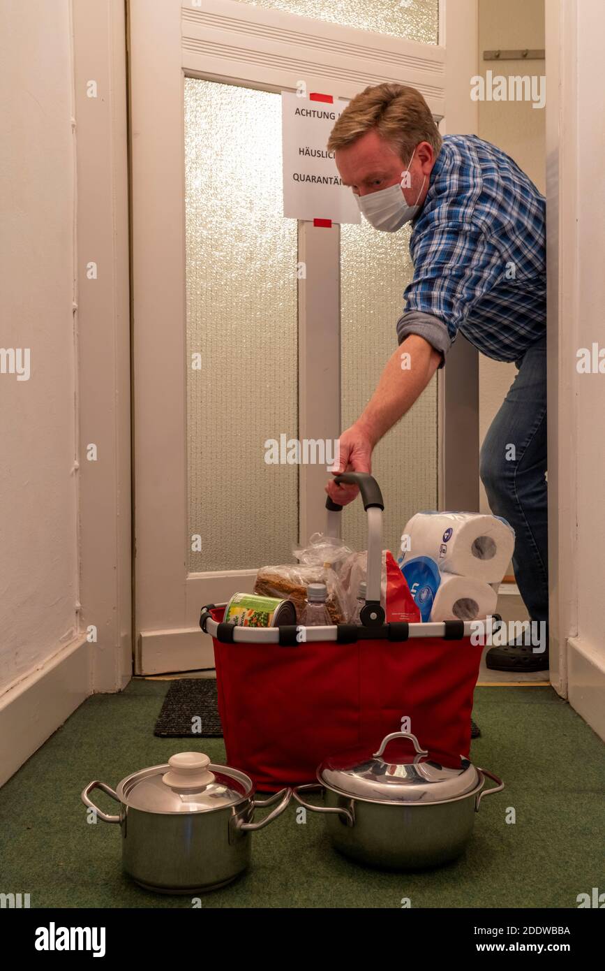 Immagine simbolica quarantena domestica, l'uomo è sospettato di infezione corona, a casa in isolamento, segnale di avvertimento per i visitatori alla porta piatta, comunicat Foto Stock