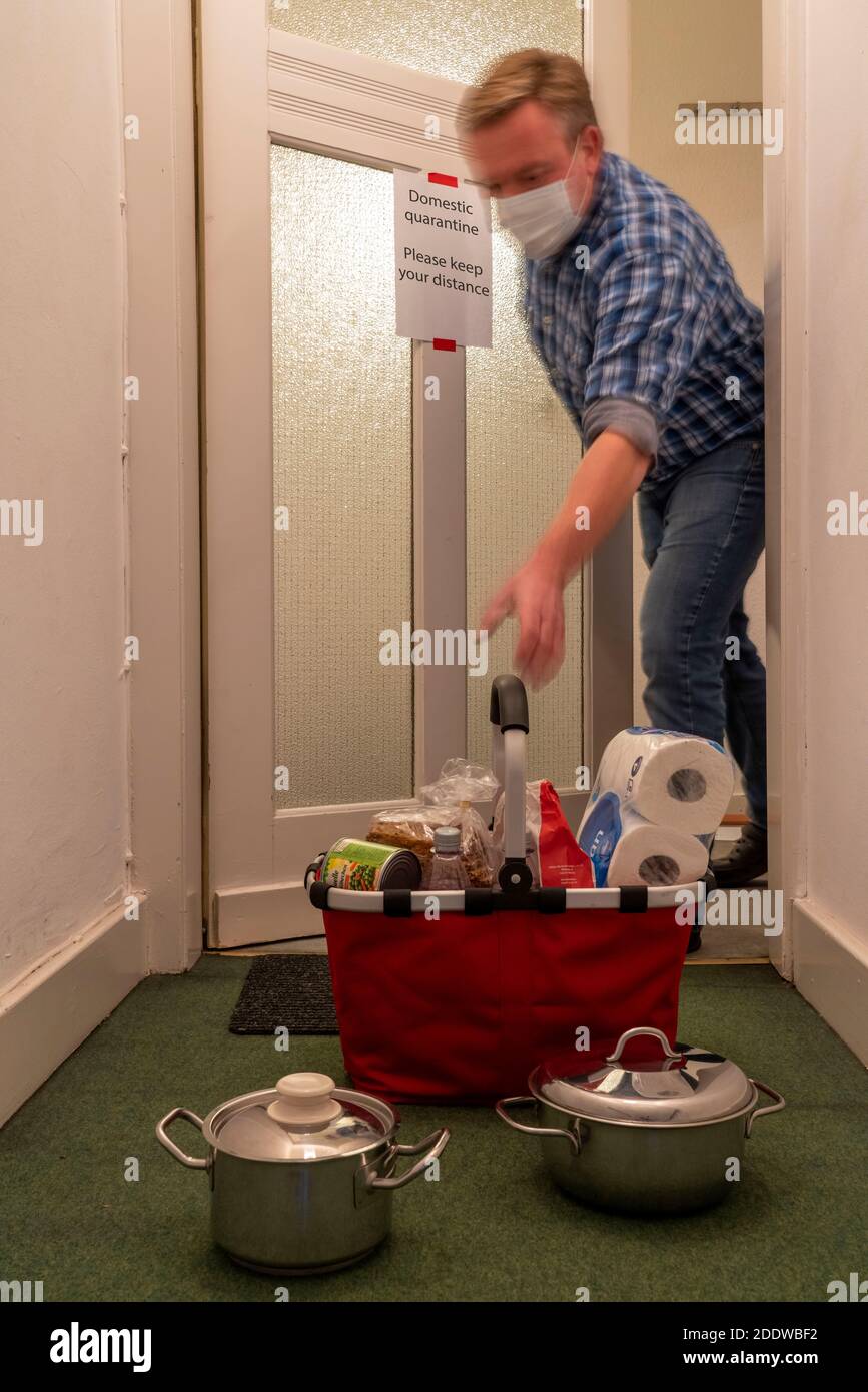 Immagine simbolica quarantena domestica, l'uomo è sospettato di infezione corona, a casa in isolamento, segnale di avvertimento per i visitatori alla porta piatta, comunicat Foto Stock