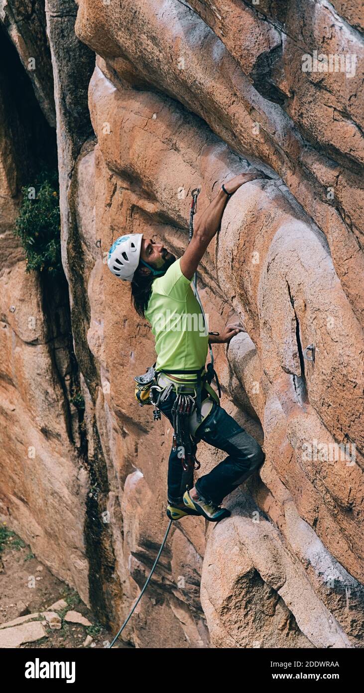 Uomo bearded che indossa casco e imbracatura facendo arrampicata su roccia. Foto Stock