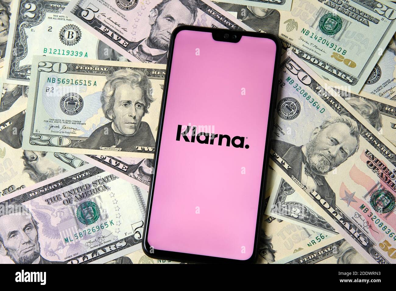 Stafford, Regno Unito - Novembre 26 2020: Schermata di login dell'app di Klarna visualizzata sullo smartphone collocato sulle banconote in dollari. Foto Stock