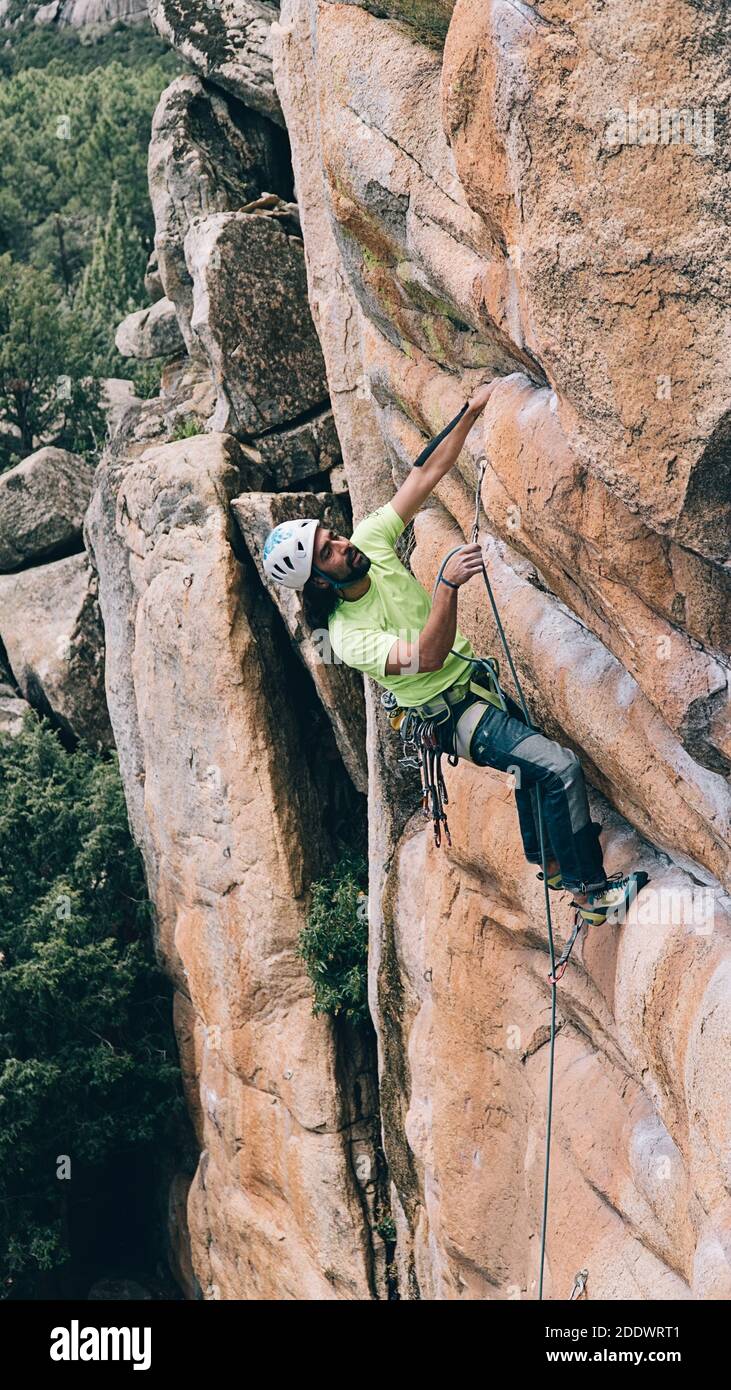 Uomo bearded che indossa casco e imbracatura facendo arrampicata su roccia. Foto Stock