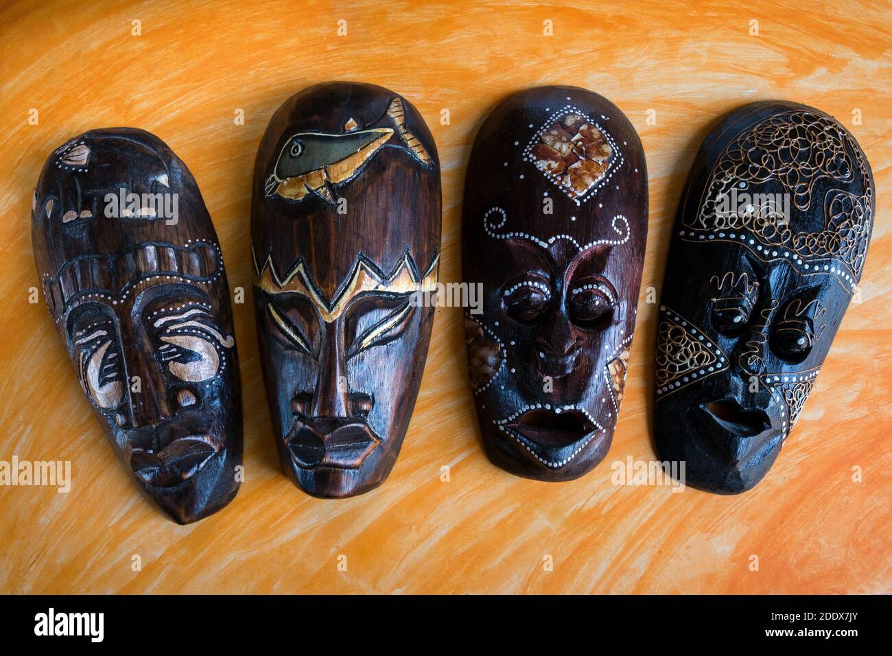 Traditiona decorate a mano maschere africane scolpite dal legno di Africano su sfondo arancione. Foto Stock