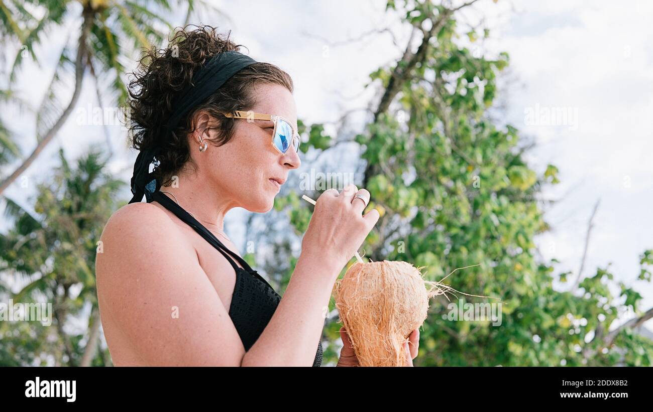 Stock foto di felice donna godendo di una giornata in spiaggia e bere acqua di cocco. Foto Stock