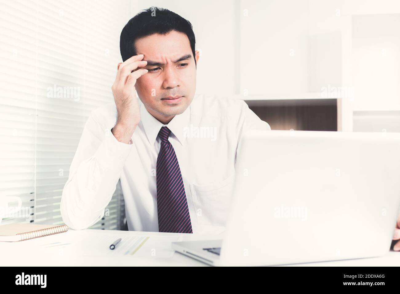 L'uomo d'affari asiatico che ottiene stressato (sconvolto) al lavoro, mettendo la sua mano sul tempiale Foto Stock