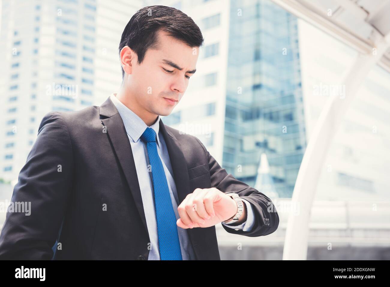 Uomo d'affari che guarda il suo orologio controllando il tempo con faccia seria Foto Stock