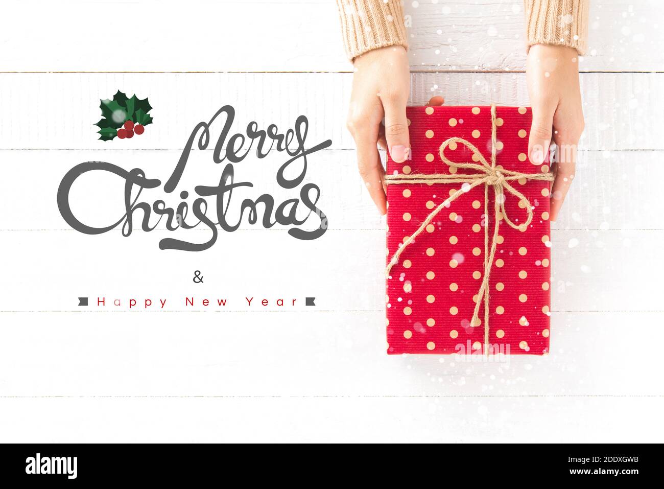 Mani che danno scatola regalo rossa con buon Natale e felice Testo del nuovo anno su sfondo di legno bianco Foto Stock