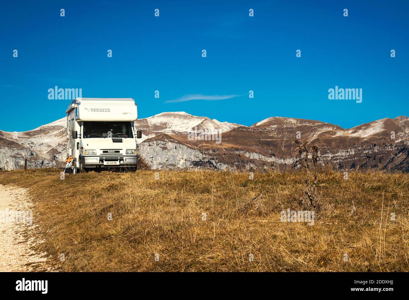 Panorama invernale dalla cima del Monte avena. Cielo limpido e catene montuose in lontananza. Un camper per turisti parcheggiato. Belluno, Italia Foto Stock