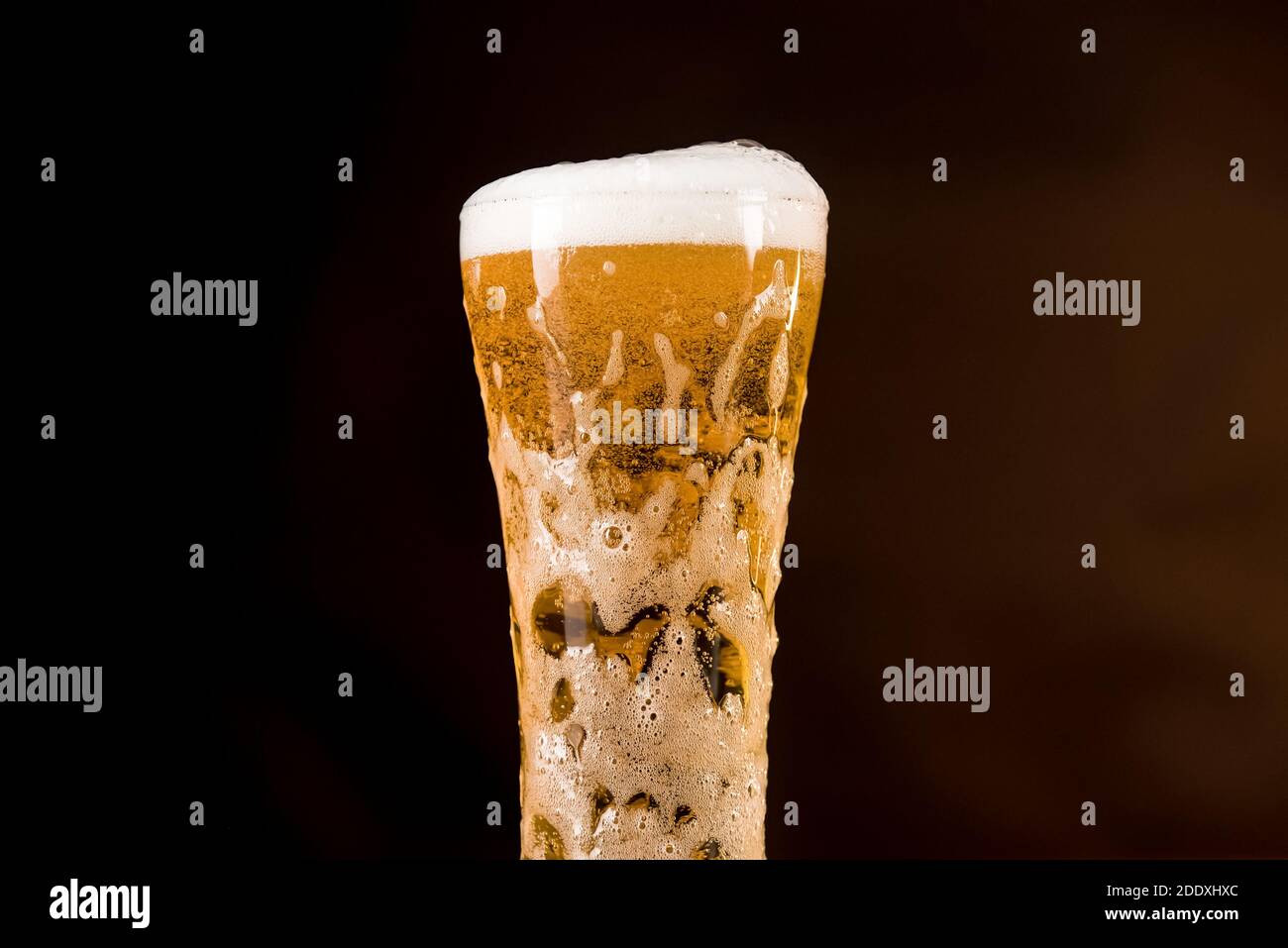 Bicchiere di bevanda alcolica di birra fredda dorata con schiuma traboccante bolle nella barra Foto Stock