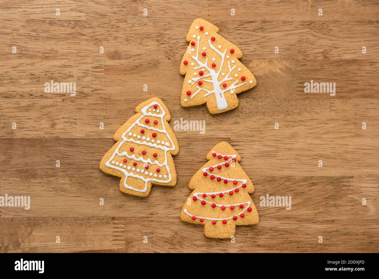 Festoso decorato Natale forma albero zenzero biscotti su sfondo legno, vista dall'alto Foto Stock