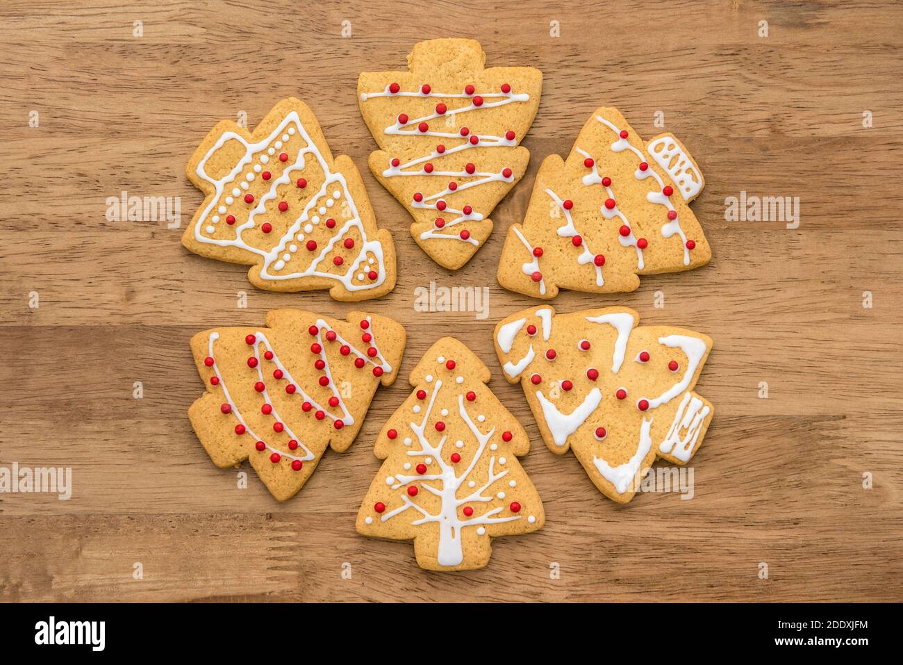 Festoso decorato Natale forma albero zenzero biscotti su sfondo legno, vista dall'alto Foto Stock