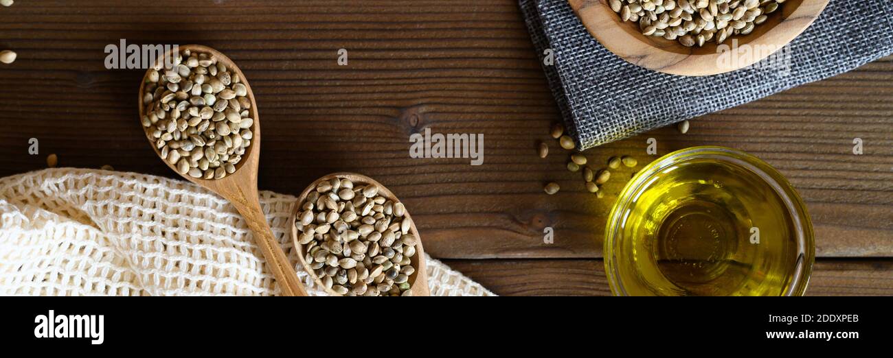 semi di cibo di canapa essiccati organici in una composizione con oggetti da cucina su uno sfondo di legno. banner piatto Foto Stock