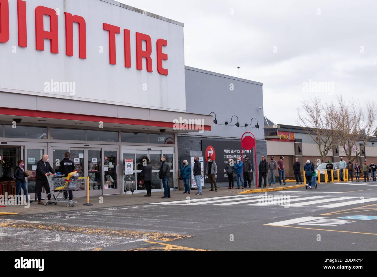 Courtenay, Canada - Nov 21,2020: Le persone si stanno allineando per entrare nel Canadian Tire Store praticando la distanza sociale tra di loro a causa di COVID-19. Foto Stock