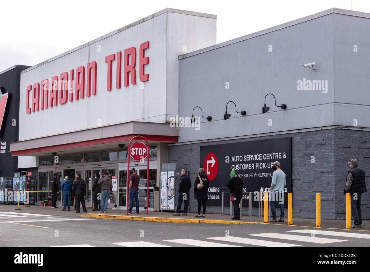 Courtenay, Canada - Nov 21,2020: Le persone si stanno allineando per entrare nel Canadian Tire Store praticando la distanza sociale tra di loro a causa di COVID-19. Foto Stock