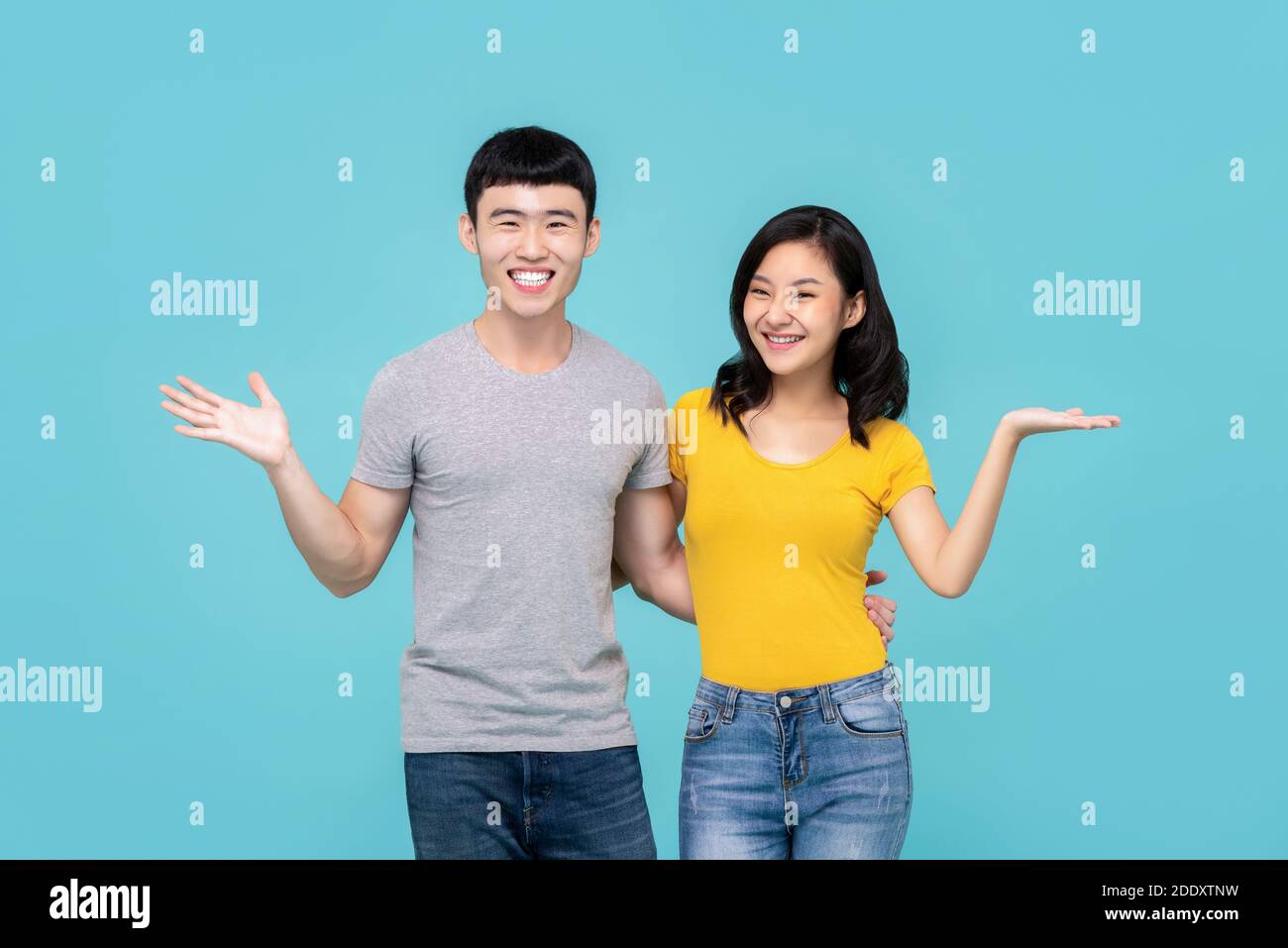 Carino giovane coppia asiatica cinese sorridente con gesti a mani aperte isolato su sfondo azzurro Foto Stock