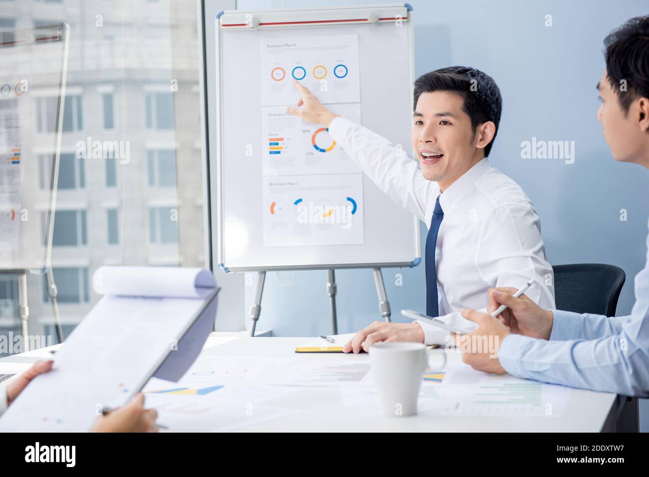 Uomo d'affari asiatico che presenta le tabelle di programma di affari alla riunione nell'ufficio Foto Stock