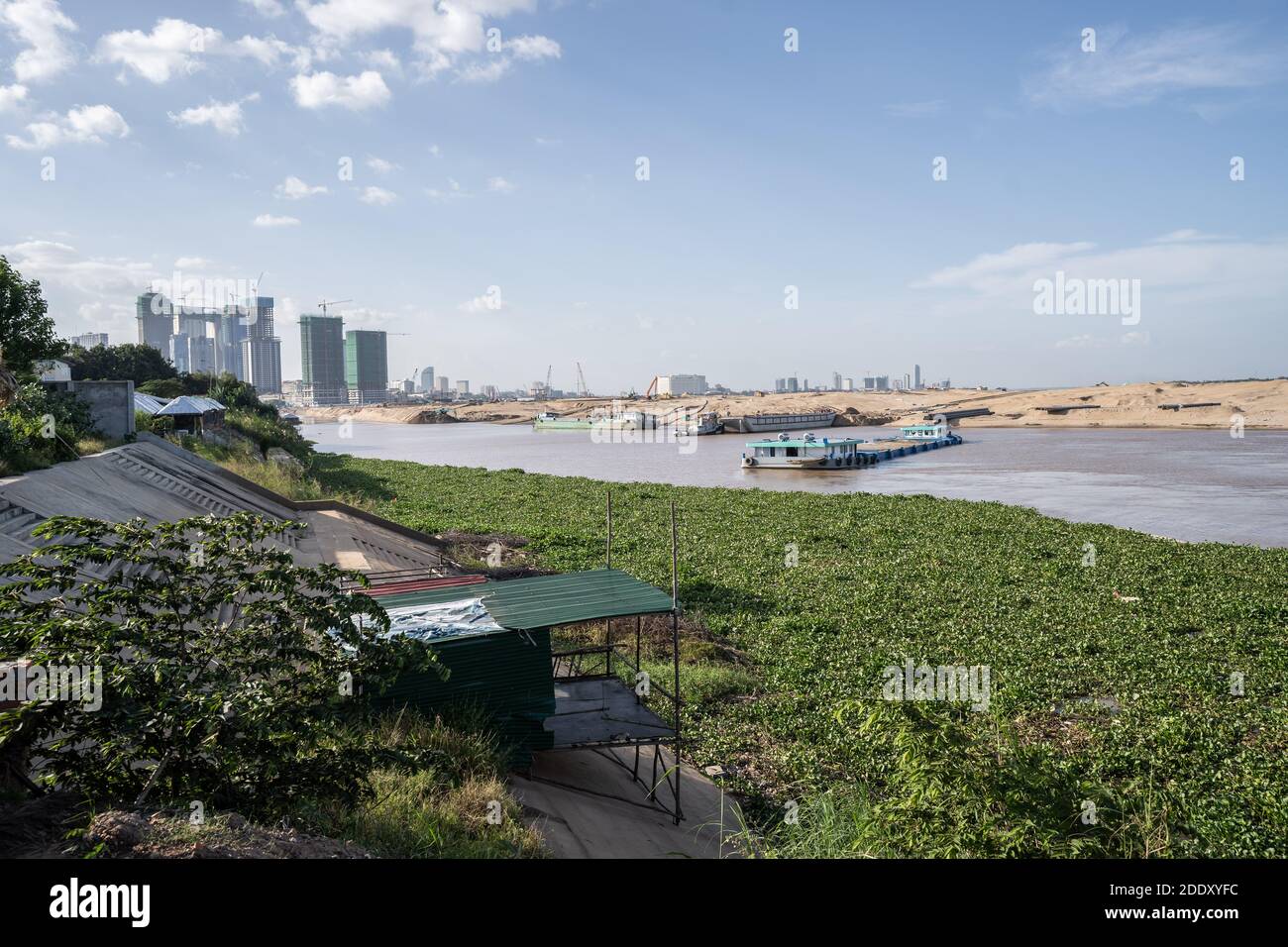 Una vista di una baracca usata dai lavoratori e dalla gente del posto per riposarsi affacciandosi sul luogo di bonifica della terra di Koh Norea.Koh Norea è l'isola più nuova di Phnom Penh, attualmente in fase di sviluppo lungo le rive del Mekong. Il progetto di bonifica di 100 ettari è stato sviluppato dalla Overseas Cambodia Investment Corporation, una delle più grandi società di sviluppo della Cambogia. Gli ambientalisti hanno sollevato preoccupazioni circa la mancanza di trasparenza del progetto, nonché il suo potenziale impatto sulla pesca locale e l'aumento del rischio di inondazioni a valle. Foto Stock