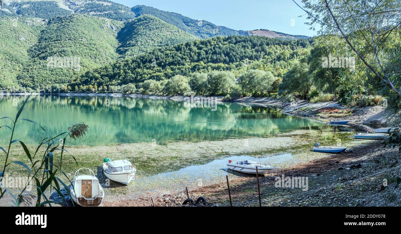Paesaggio con barche a riva e verde riva boscosa che si riflette nelle acque limpide del lago di Scanno, sparato in luce brillante vicino Appenninia, l'Aquila, Abruzzo, Foto Stock