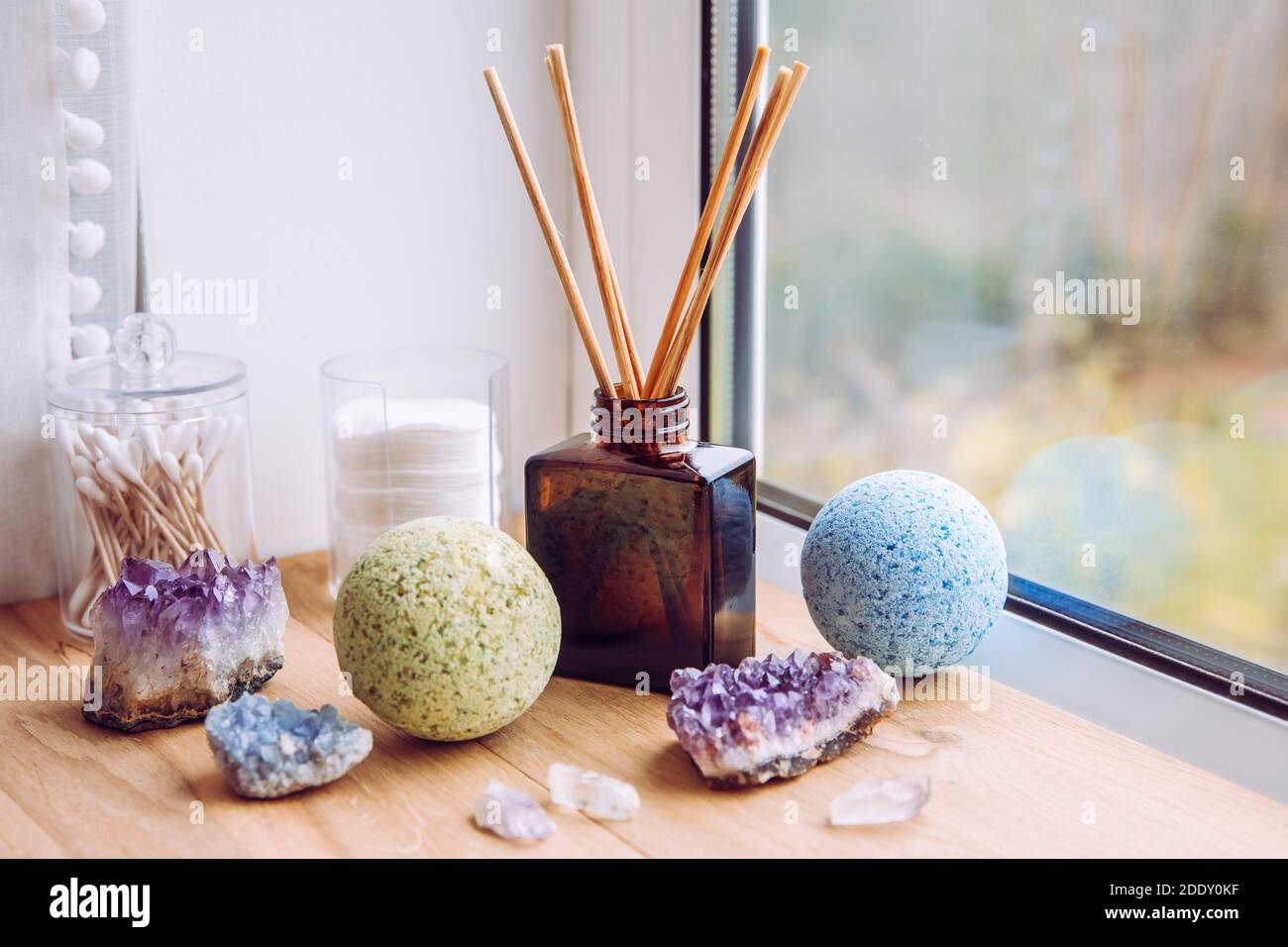 Davanzale finestra bagno in legno naturale con flacone diffusore di liquido con bastoncini in legno, luce naturale proveniente dalla finestra. Blu e verde rilassante. Foto Stock