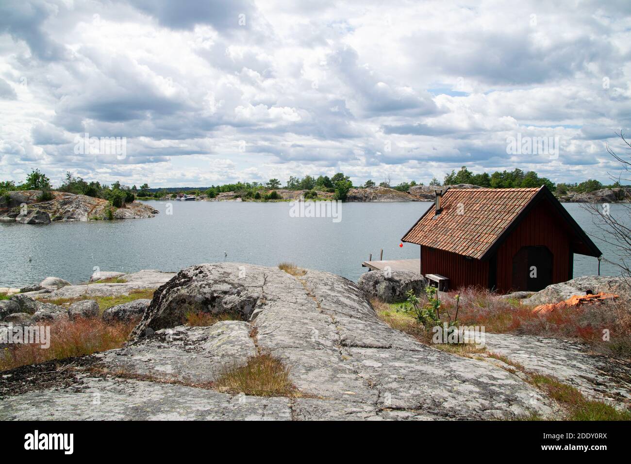 Piccolo edificio in legno rosso vicino al mare nell'arcipelago svedese in una giornata estiva. Foto scattata in Svezia. Foto Stock