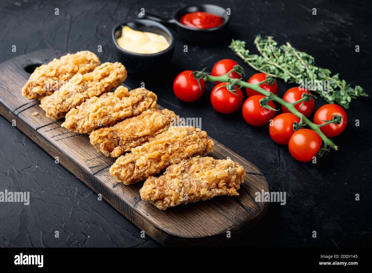 Le ali di pollo fritte e speziate impanate si tagliano su sfondo nero. Foto Stock