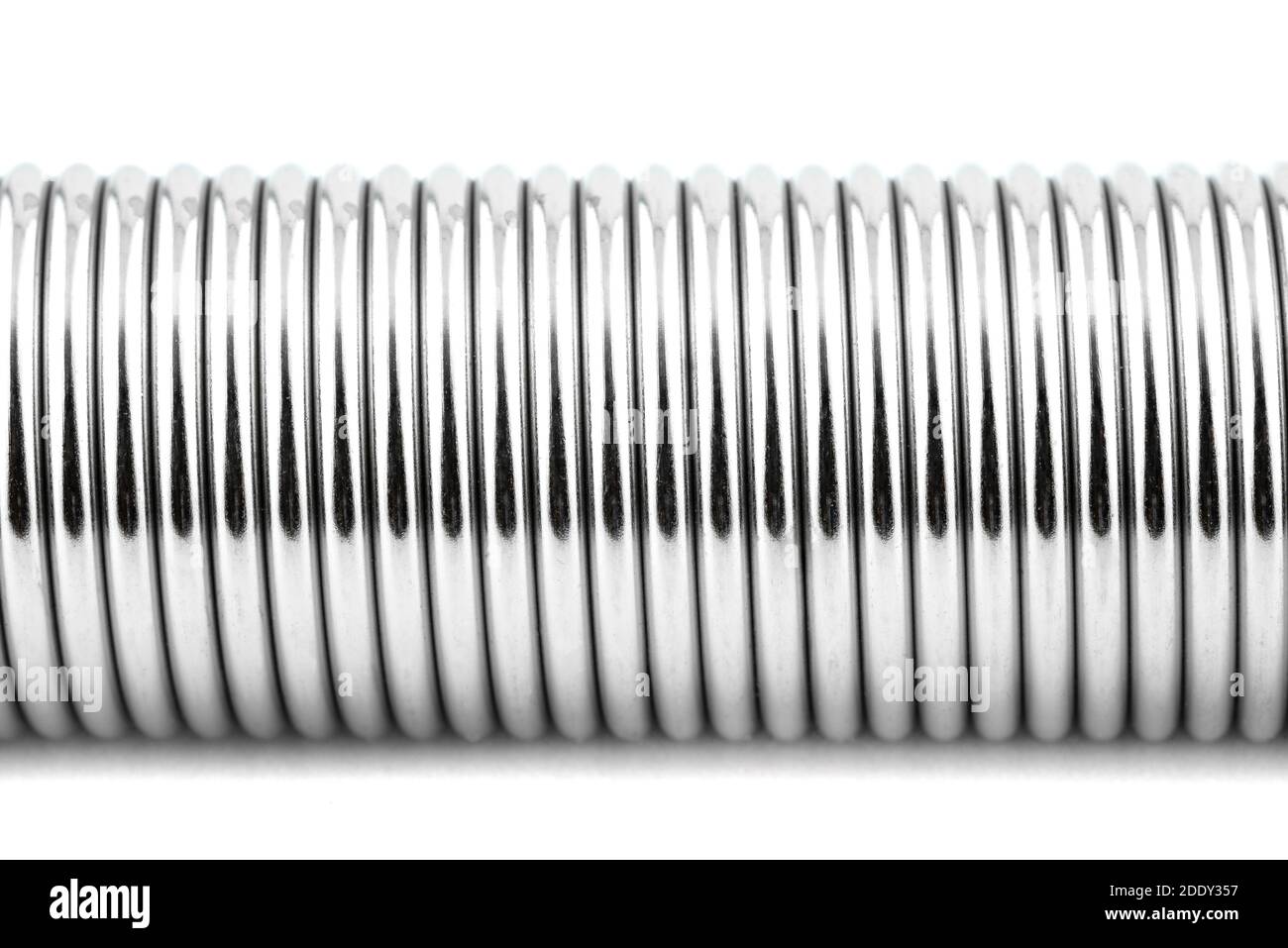 Una macro di una nuova molla in acciaio, isolata su sfondo bianco. Foto Stock