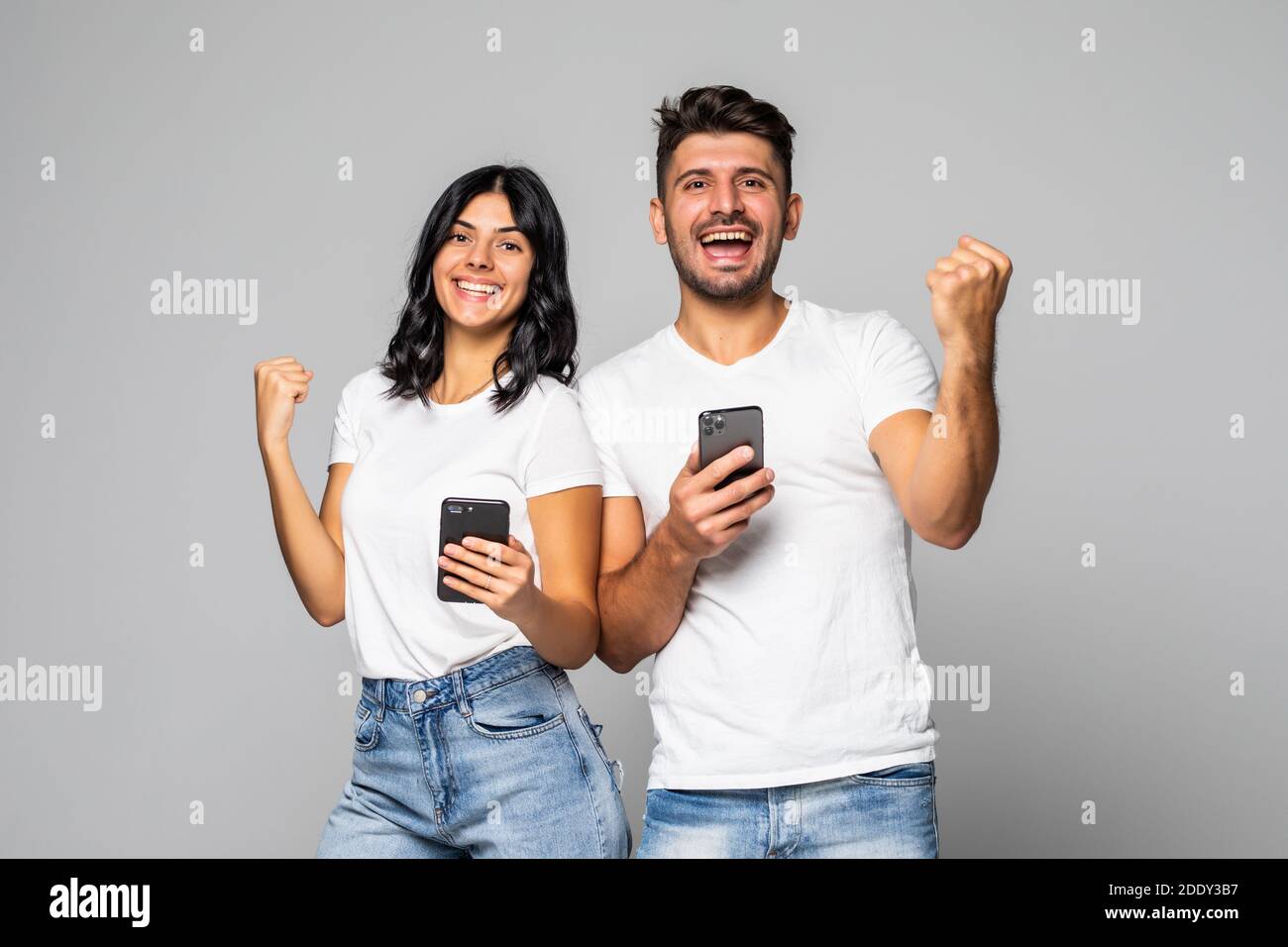 Coppia o amici con grande gioia in possesso di smartphone, ricevuto messaggio con lotteria online annuncio di vittoria, celebrando inaspettato successo, isolato su gr Foto Stock