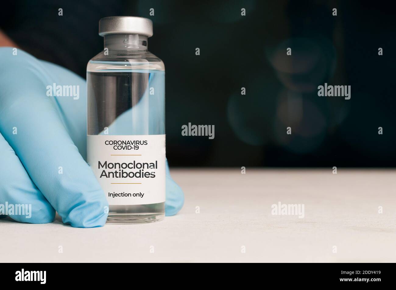 Il medico tiene una fiala di anticorpi monoclonali , un nuovo trattamento per il coronavirus Covid-19, su un tavolo bianco Foto Stock