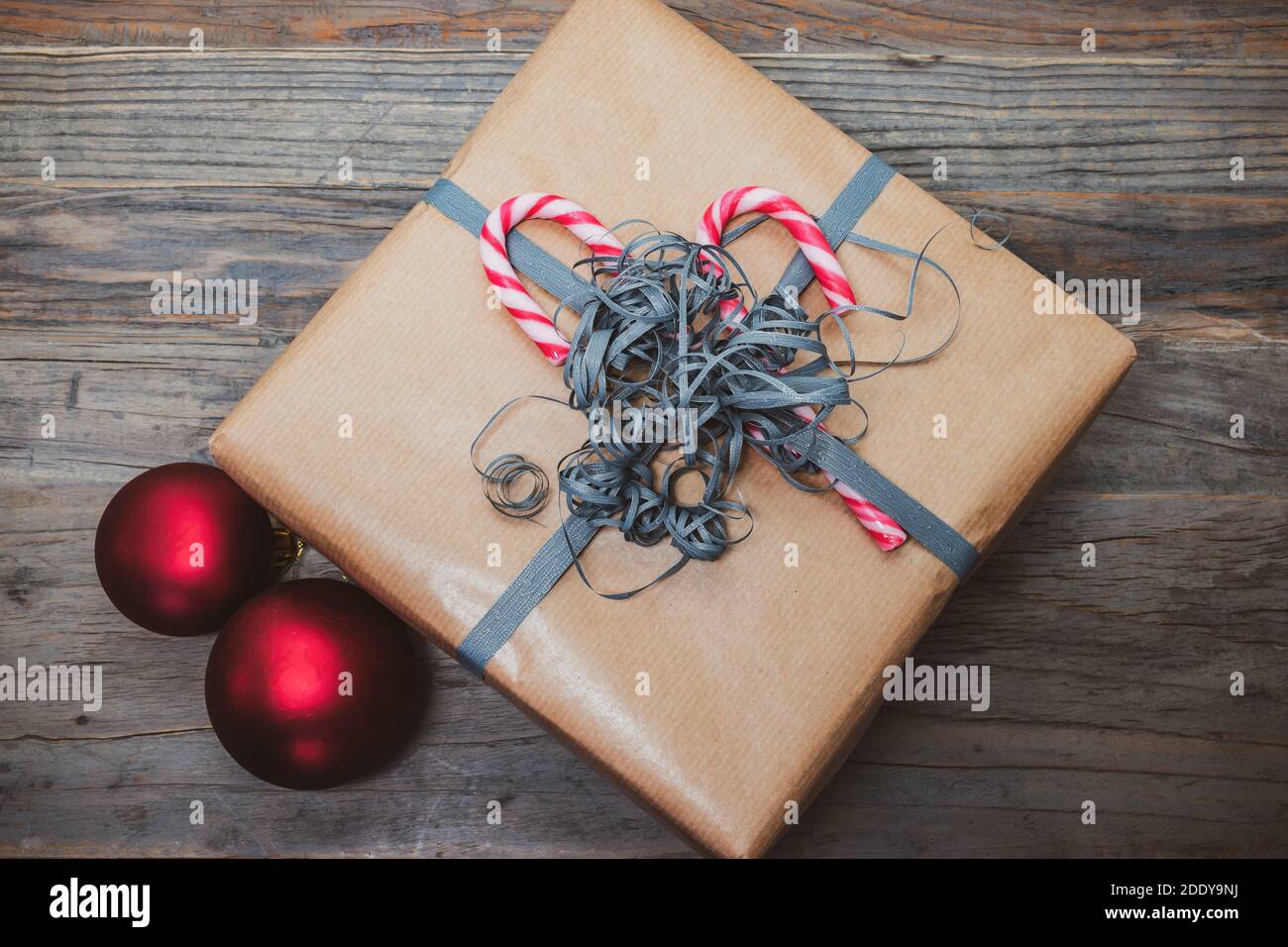Scatola regalo di Natale marrone decorata con canne caramelle e nastro di avvolgimento arricciato. Foto Stock