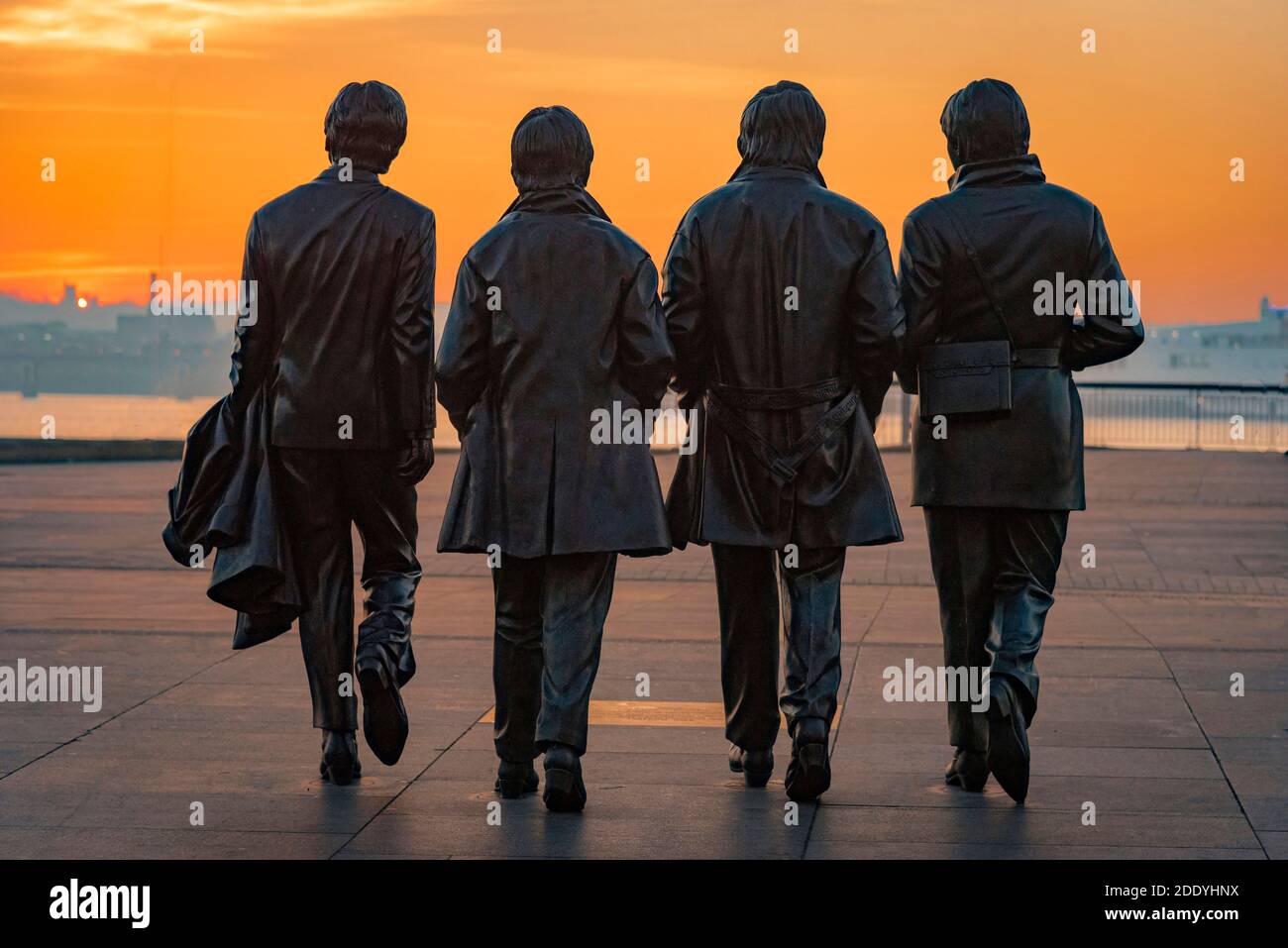 Statua dei Beatles o dei Fab Four a Liverpool Pierhead al sole della sera. Un lampione hs è stato spazzolato dall'aria da questa immagine. Foto Stock