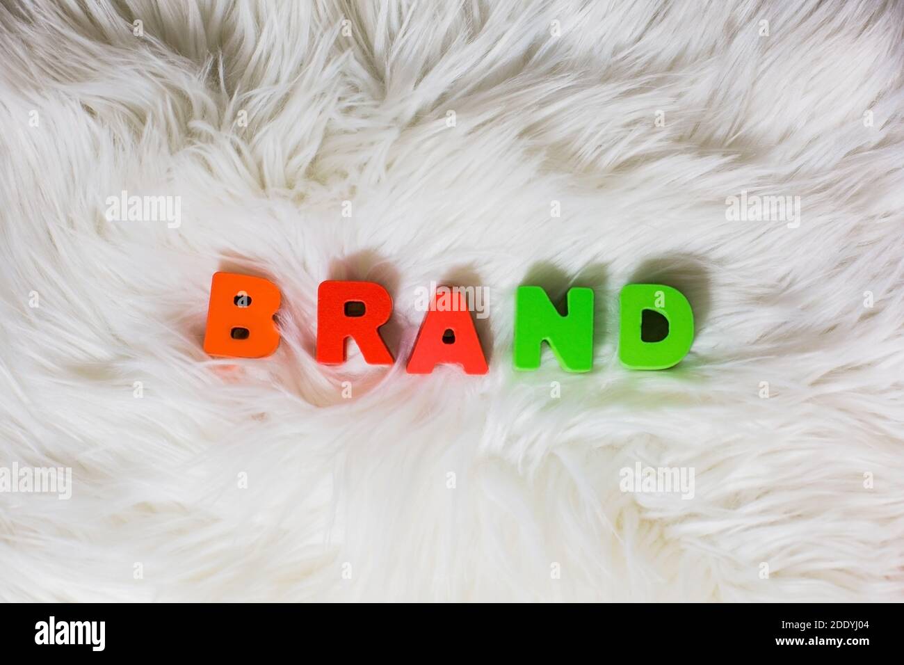 Ortografia del marchio di parola da lettere abc colorate in legno fluffly, faux fur bianco sfondo, moda, industrie dei social media, concetto di stile Foto Stock