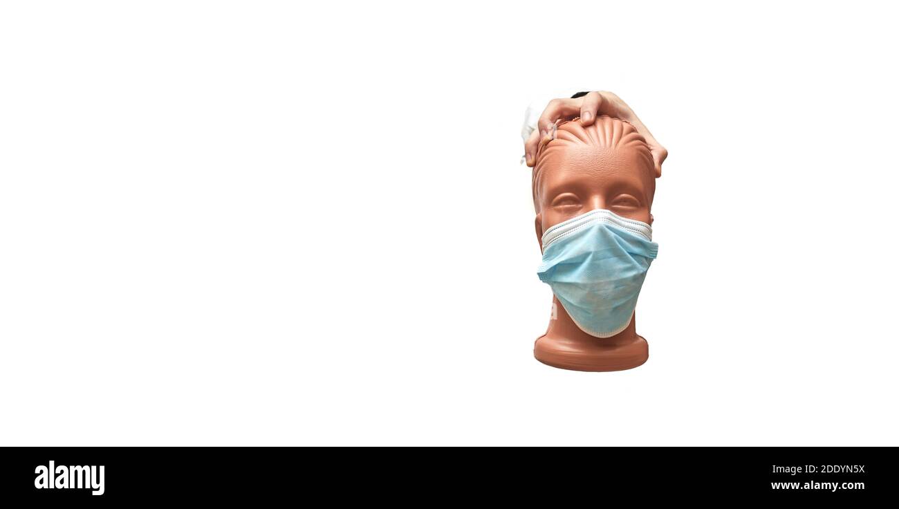la mano tiene un manichino con una maschera medica su uno sfondo bianco isolato, banner, spazio per la copia Foto Stock